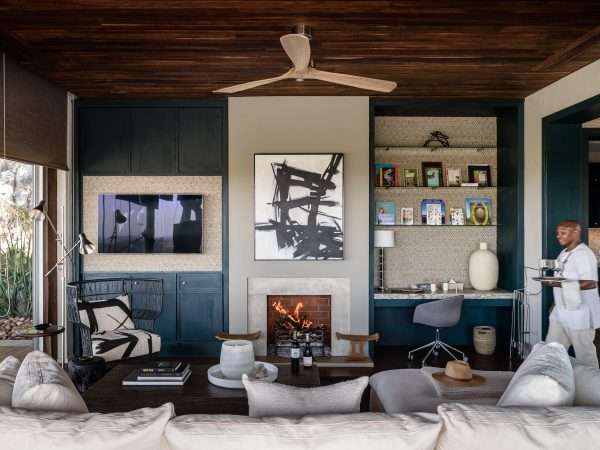 Hillside-Suite-Singita-Sasakwa-Lodge-Lounge-Area-with-Fireplace-and-Staff