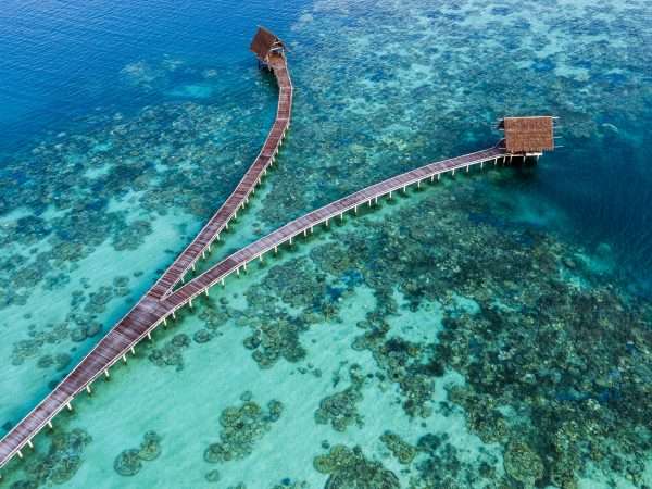 aerial_wooden_jetty_with_thatched_roof_coral_reefs_lagoon